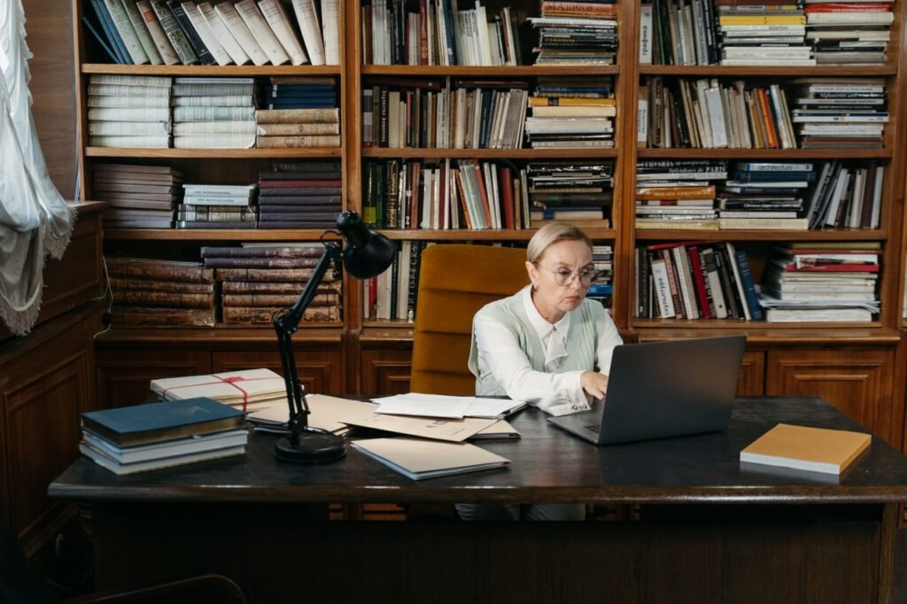 Mastering the First Impression: Your intriguing post title goes here Businesswoman engaging in remote work at a desk surrounded by books. Perfect setup for productivity.